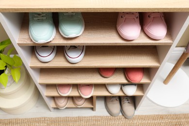 Photo of Different stylish shoes in storage unit, above view. Dressing room interior