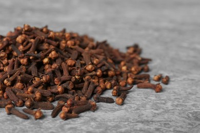 Photo of Pile of aromatic dry cloves on grey table, closeup