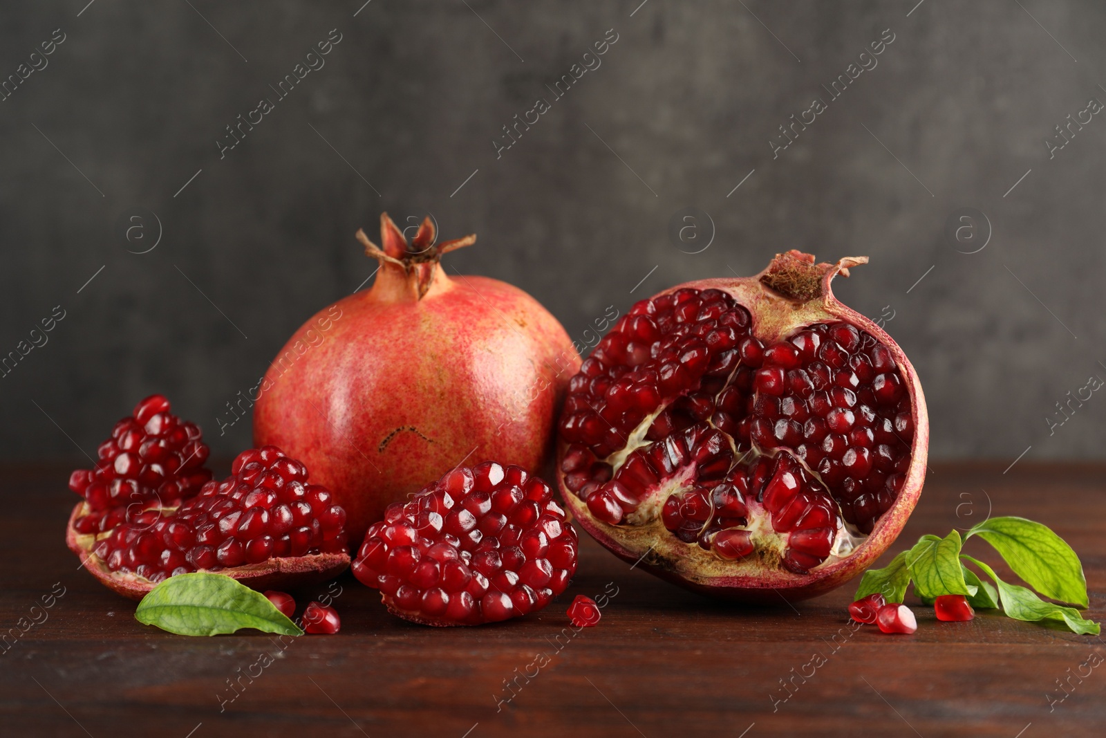 Photo of Fresh pomegranates and green leaves on wooden table