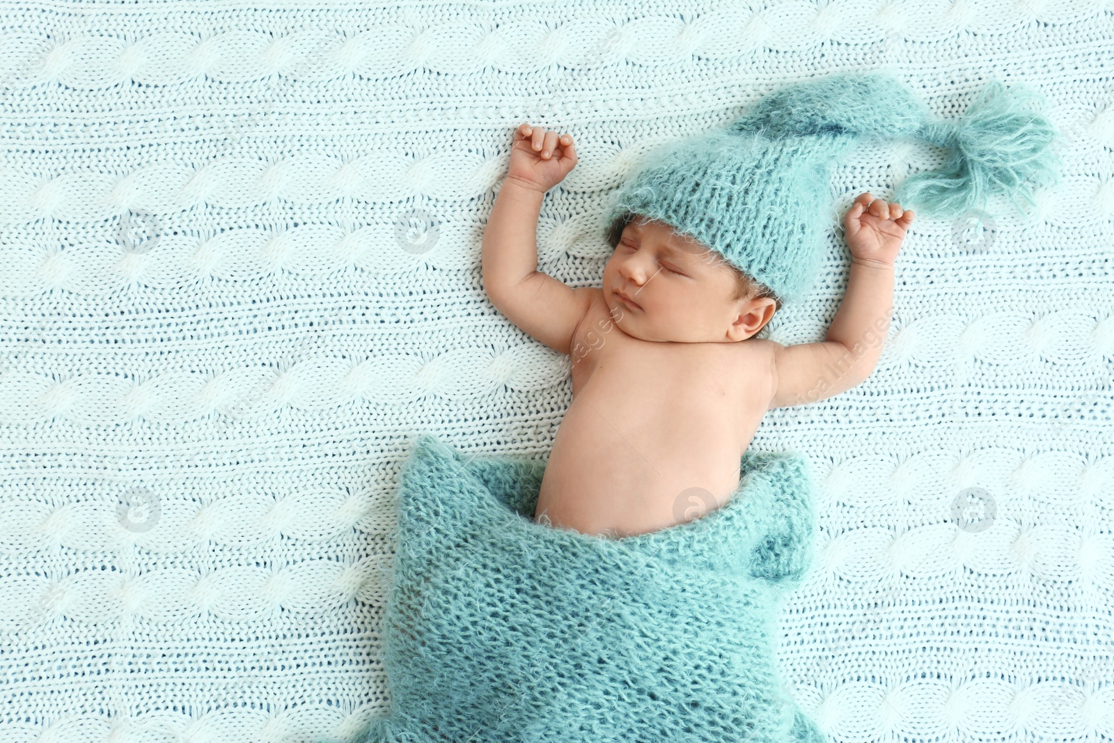 Photo of Cute little baby in green hat lying on soft blanket, top view. Space for text