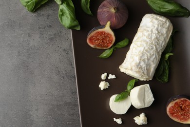 Photo of Delicious goat cheese with figs and basil on grey table, above view. Space for text