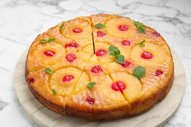 Photo of Delicious cut pineapple pie with cherry and mint on white marble table, closeup