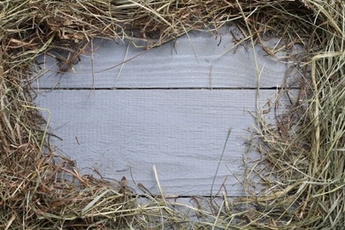 Photo of Frame made of dried hay on grey wooden table, top view. Space for text