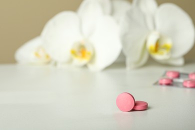 Photo of Pink pills on white table, space for text. Menopause concept
