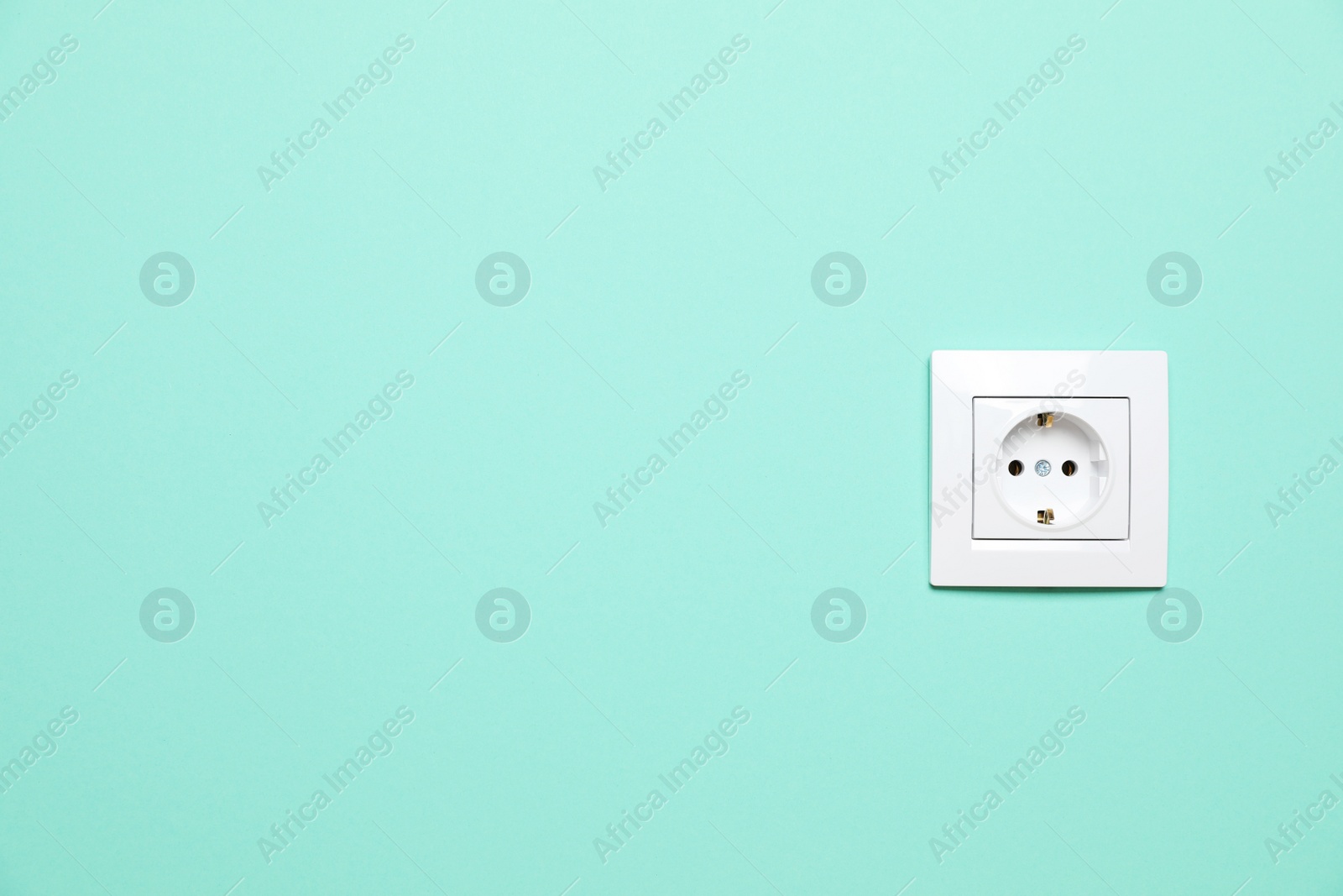 Photo of Power socket on turquoise wall, space for text. Electrical supply