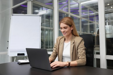 Woman working on laptop at black desk in office