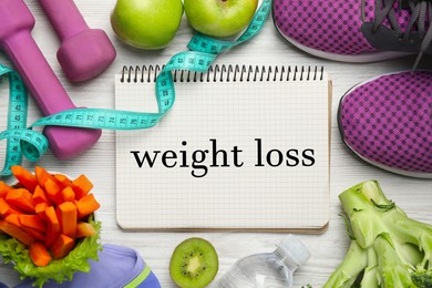 Photo of Weight loss concept. Flat lay composition with notebook, sneakers and different products on white wooden table