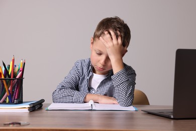 Photo of Little boy with stationery suffering from dyslexia at wooden table