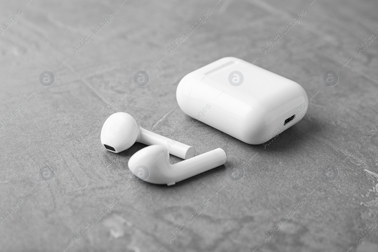 Photo of Wireless earphones and charging case on grey stone table