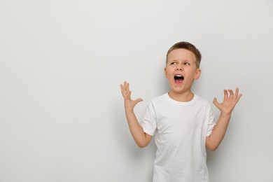 Angry little boy screaming on white background, space for text. Aggressive behavior