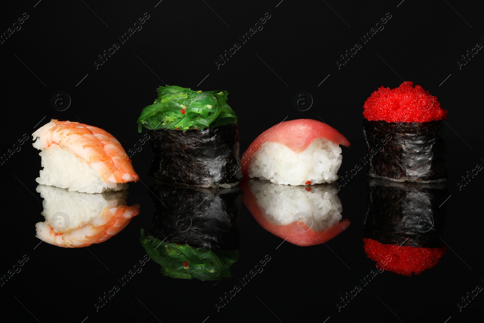 Photo of Set of delicious sushi on black mirror surface