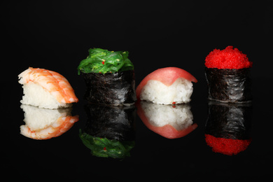 Photo of Set of delicious sushi on black mirror surface