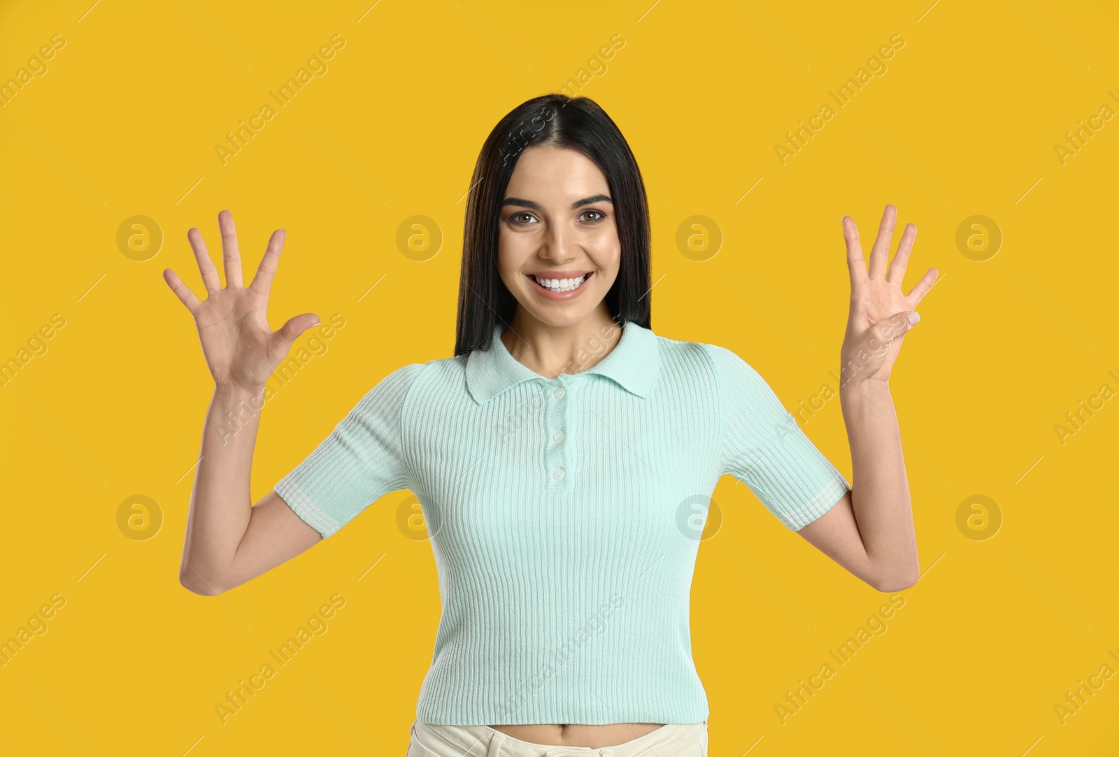 Photo of Woman showing number nine with her hands on yellow background