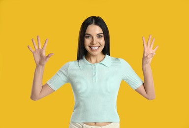 Woman showing number nine with her hands on yellow background