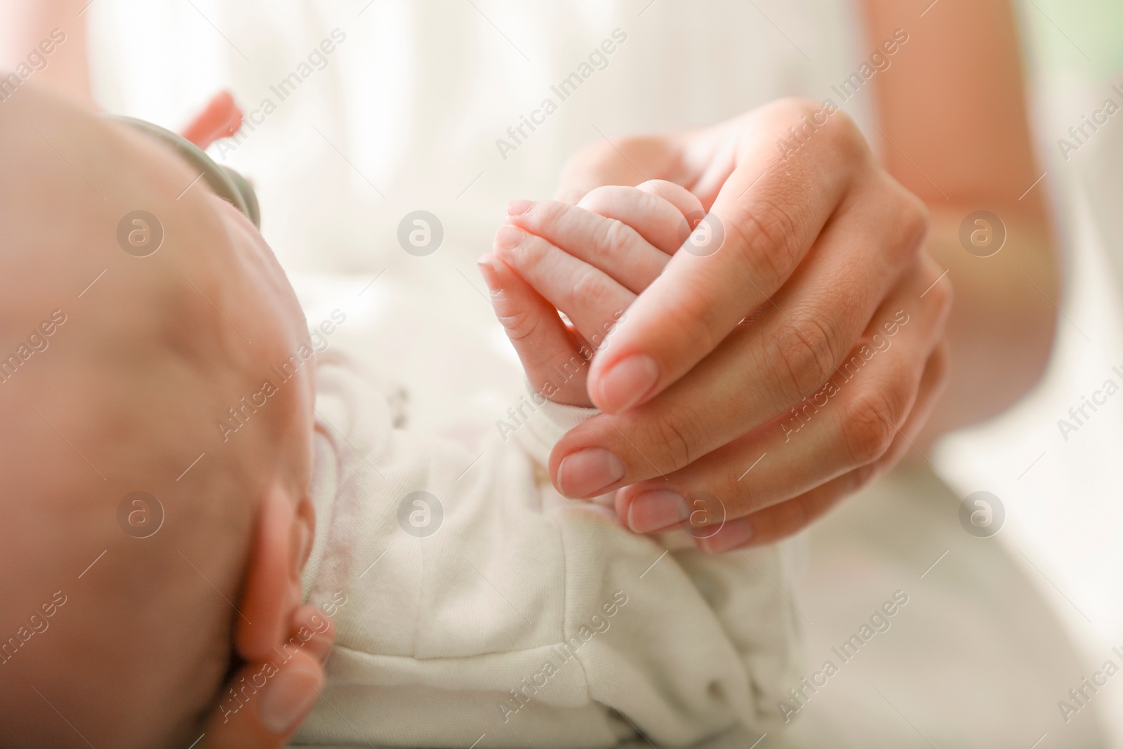 Photo of Mother holding newborn baby indoors, focus on hands