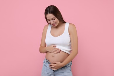 Photo of Beautiful pregnant woman with long hair on pink background