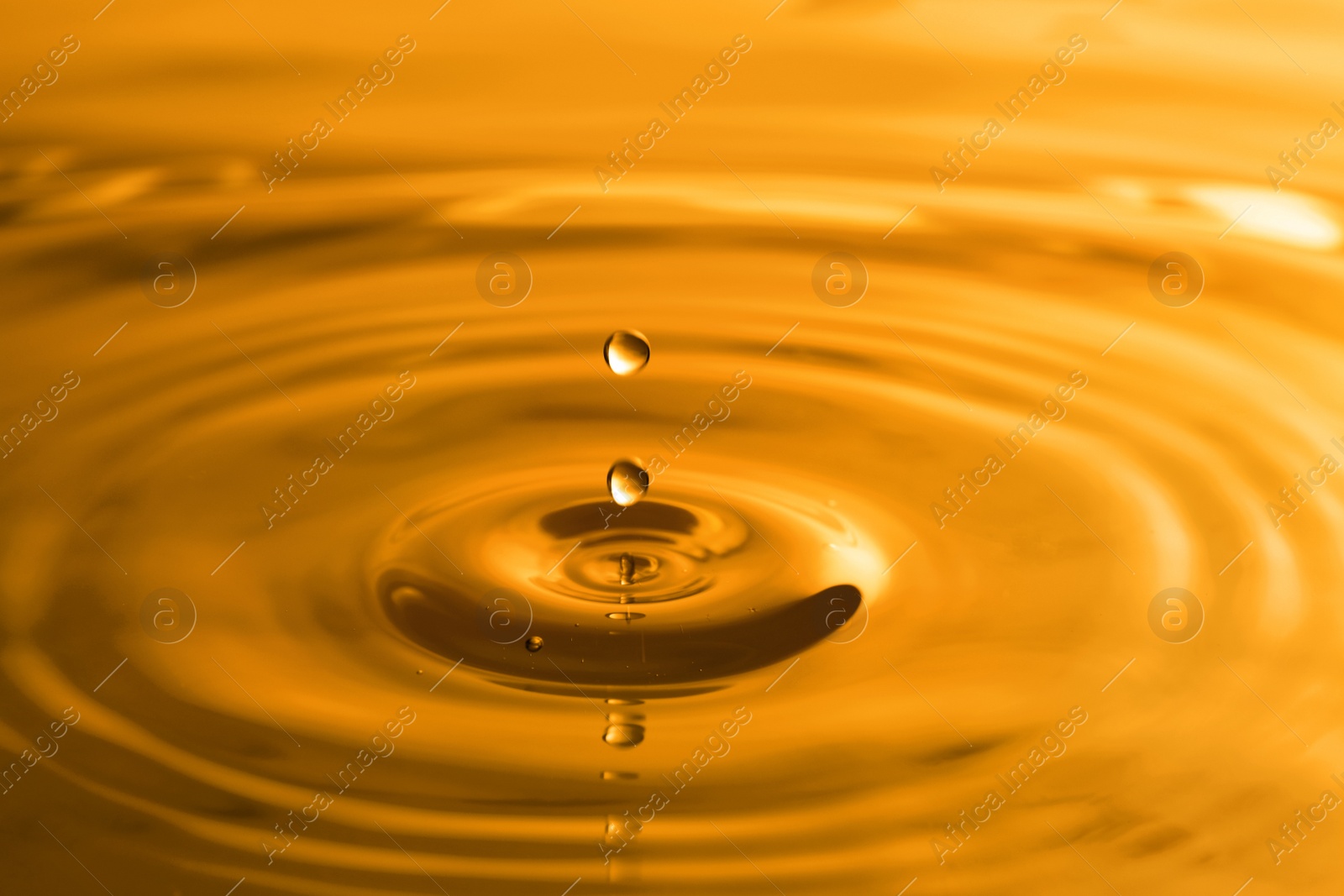 Image of Splash of golden oily liquid with drops as background, closeup