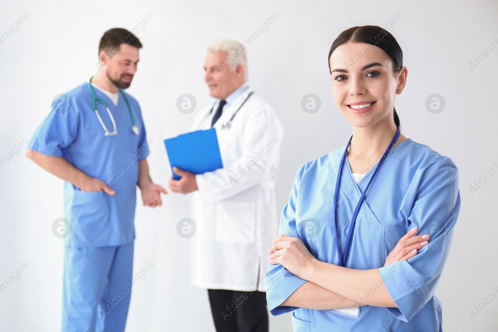 Photo of Young doctor with colleagues on light background