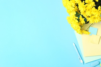 Photo of Different school stationery and beautiful yellow flowers on light blue background, flat lay with space for text. Happy Teacher's Day