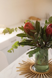 Bouquet with beautiful protea flowers on table in kitchen. Interior design