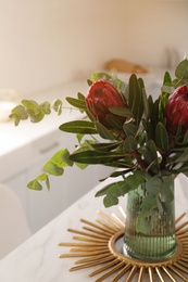 Photo of Bouquet with beautiful protea flowers on table in kitchen. Interior design