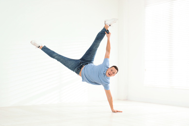 Photo of Handsome young man doing trick indoors. Modern dance