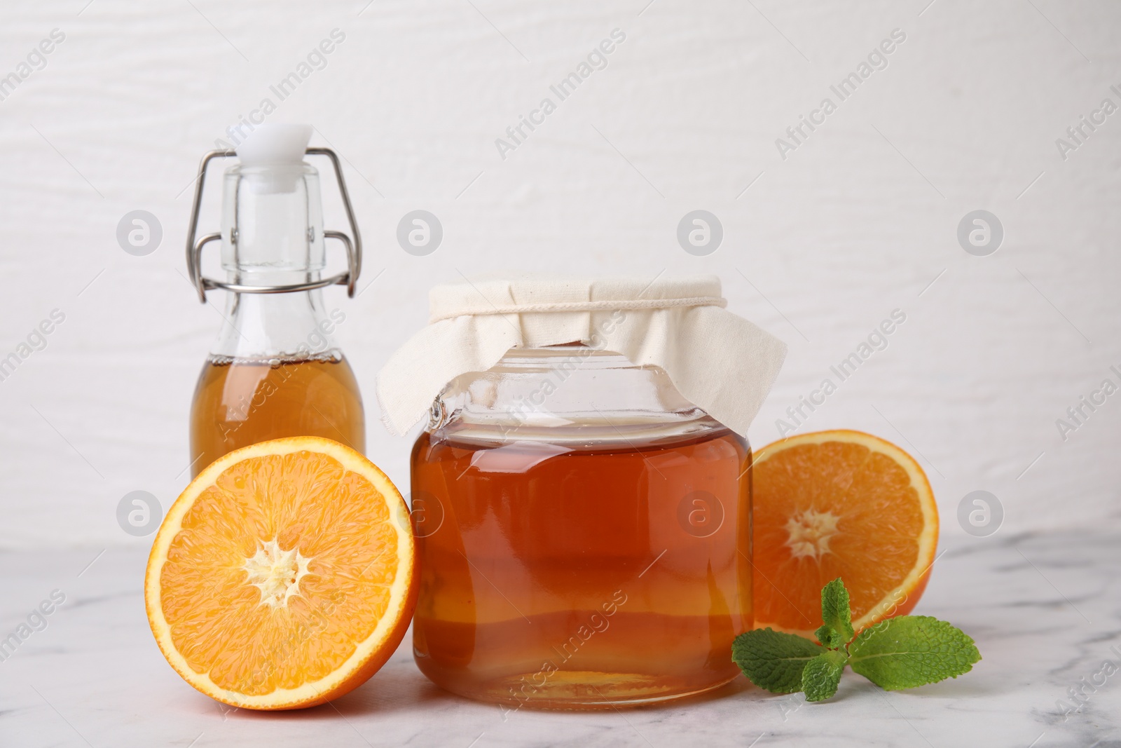 Photo of Tasty kombucha, orange and mint on white marble table