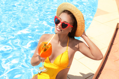 Photo of Woman with glass of refreshing drink near swimming pool