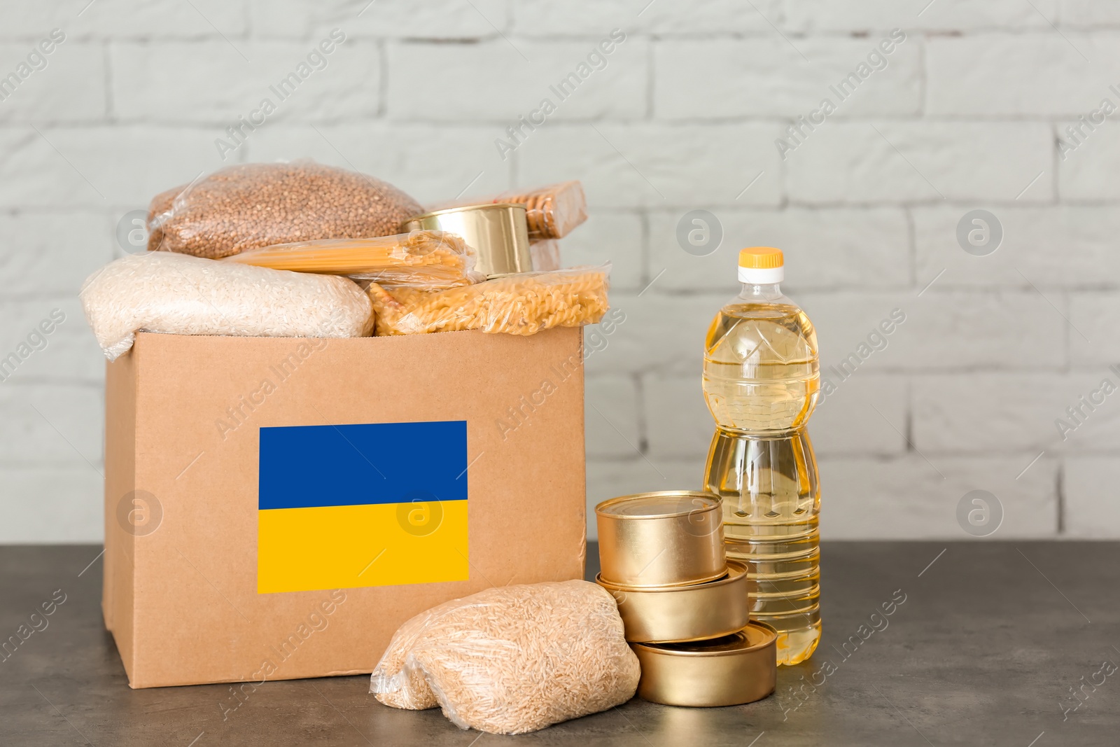 Image of Humanitarian aid for Ukrainian refugees. Donation box with food on table against brick wall