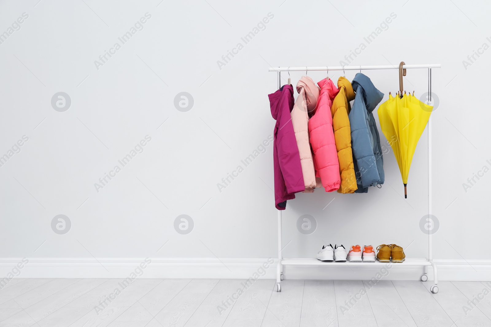 Photo of Rack with warm jackets in room. Space for text