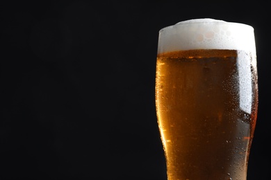 Photo of Cold tasty beer on black background, closeup. Space for text