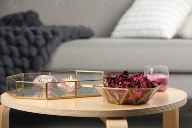 Photo of Aromatic potpourri of dried flowers in bowl and burning candles on table indoors