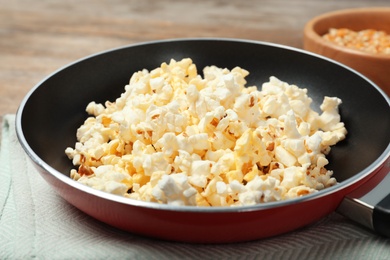 Photo of Frying pan with tasty popcorn on table