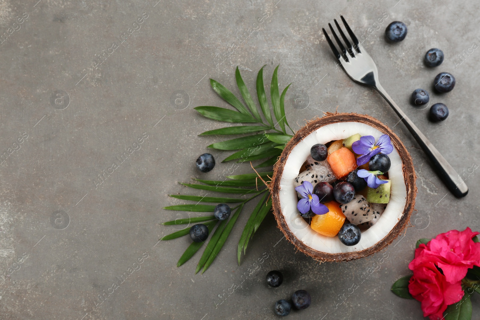 Photo of Delicious exotic fruit salad served on grey table, flat lay. Space for text