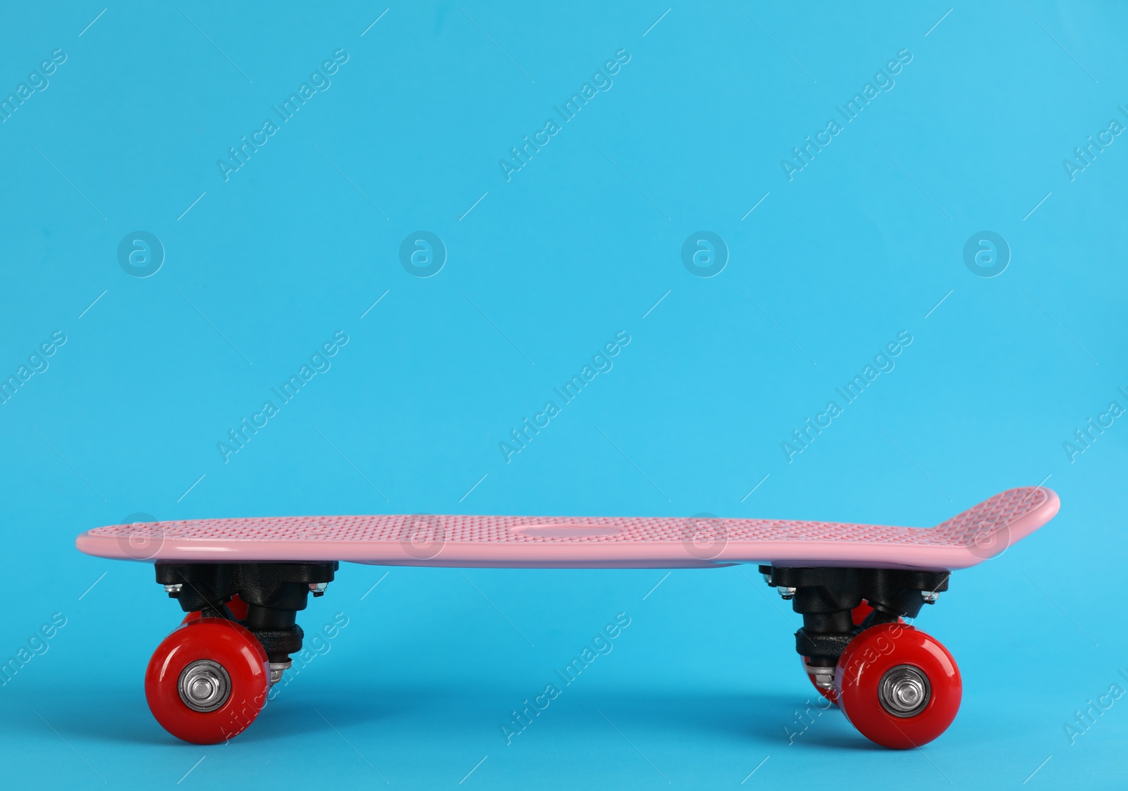 Photo of Pink skateboard on light blue background. Space for text