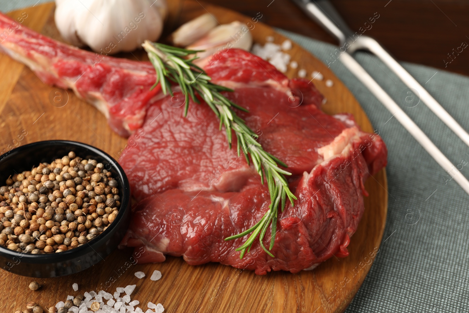 Photo of Raw ribeye steak and spices on table, closeup