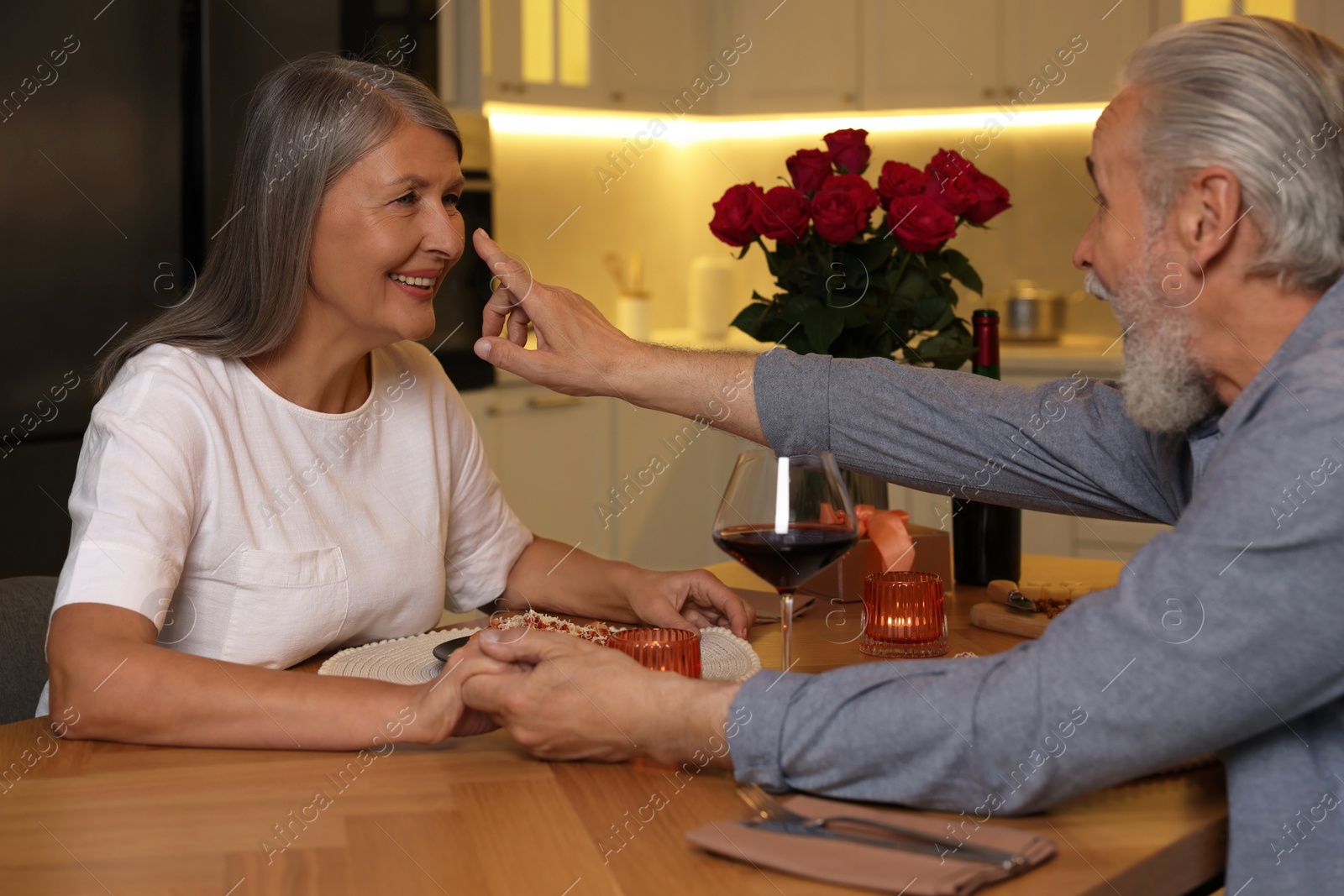 Photo of Affectionate senior couple having romantic dinner at home