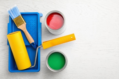 Flat lay composition with cans of paint, brush and renovation tools on white wooden background. Space for text