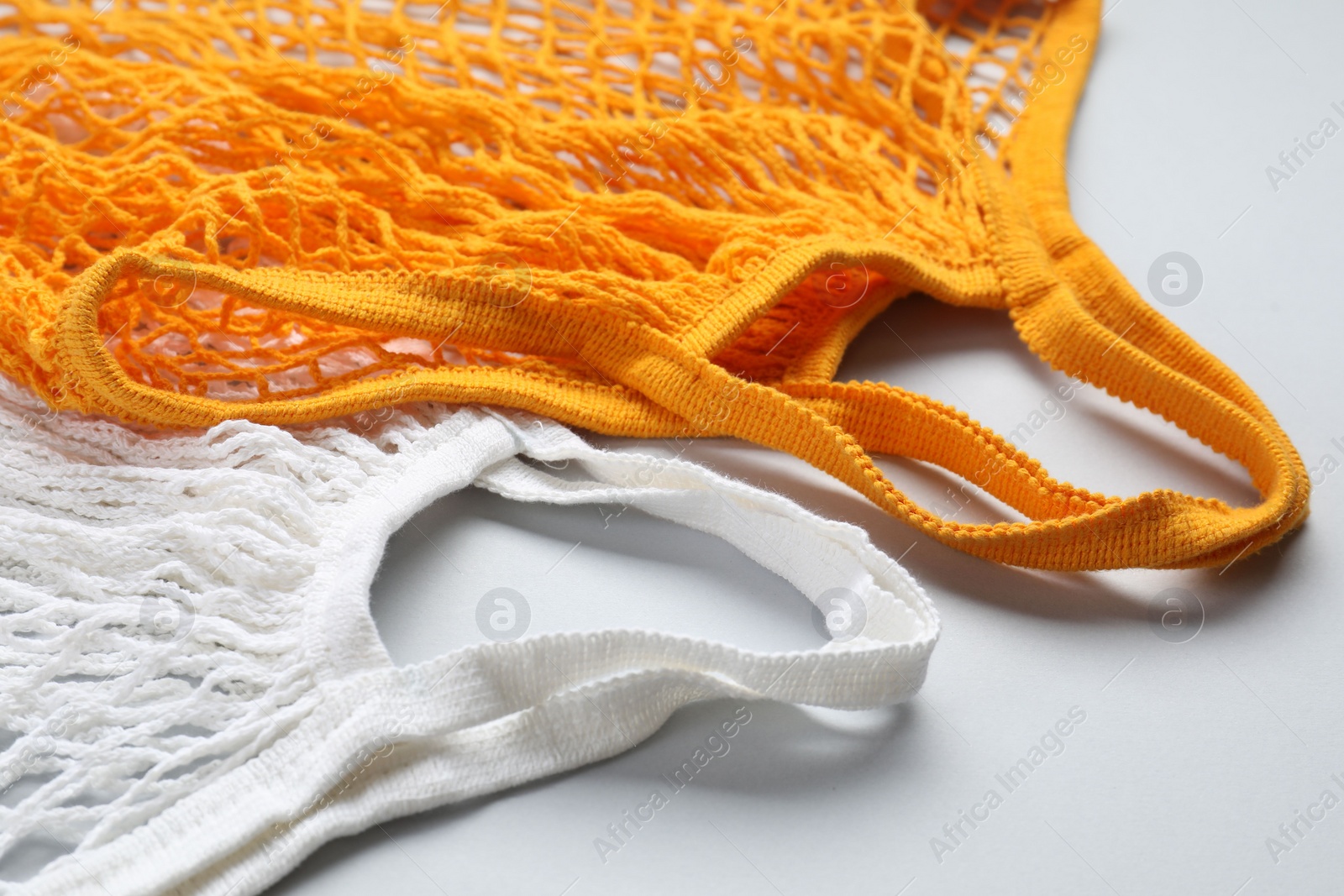 Photo of Orange and white string bags on light grey background, closeup