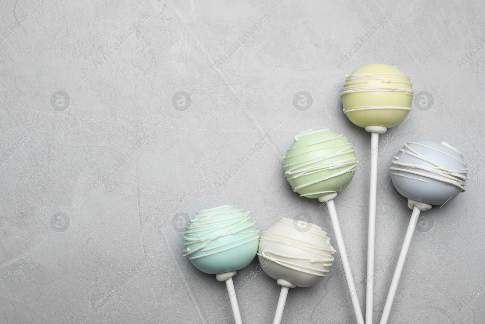 Photo of Sweet cake pops on light grey background, flat lay. Space for text