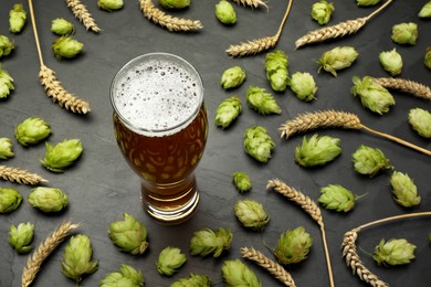 Photo of Glass of beer, fresh green hops and spikes on dark grey table