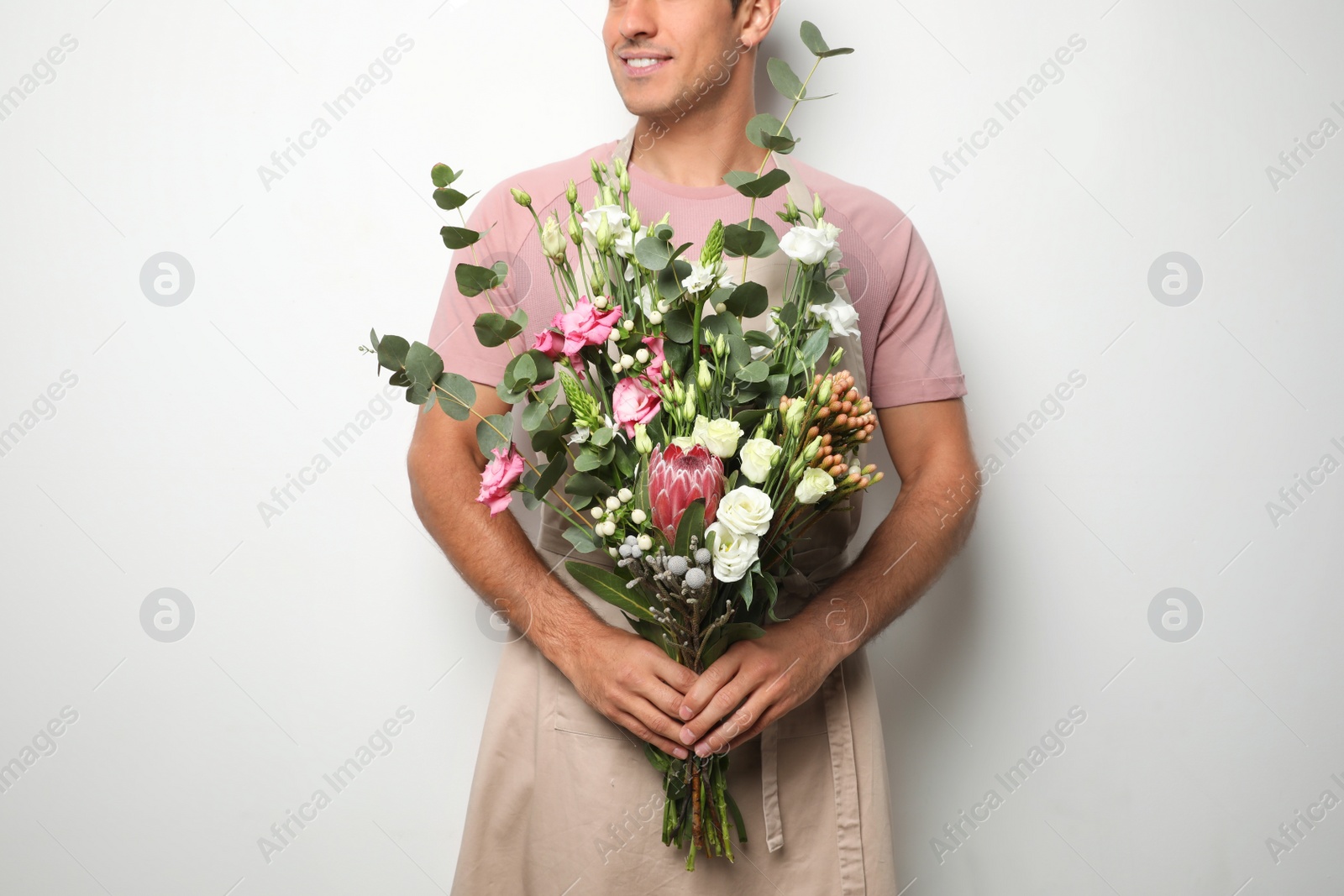 Photo of Florist with beautiful bouquet on light background, closeup