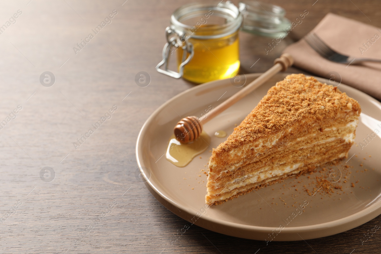 Photo of Slice of delicious layered honey cake served on wooden table. Space for text