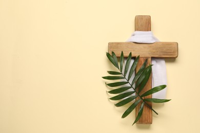 Photo of Wooden cross, white cloth and palm leaf on beige background, top view with space for text. Easter attributes