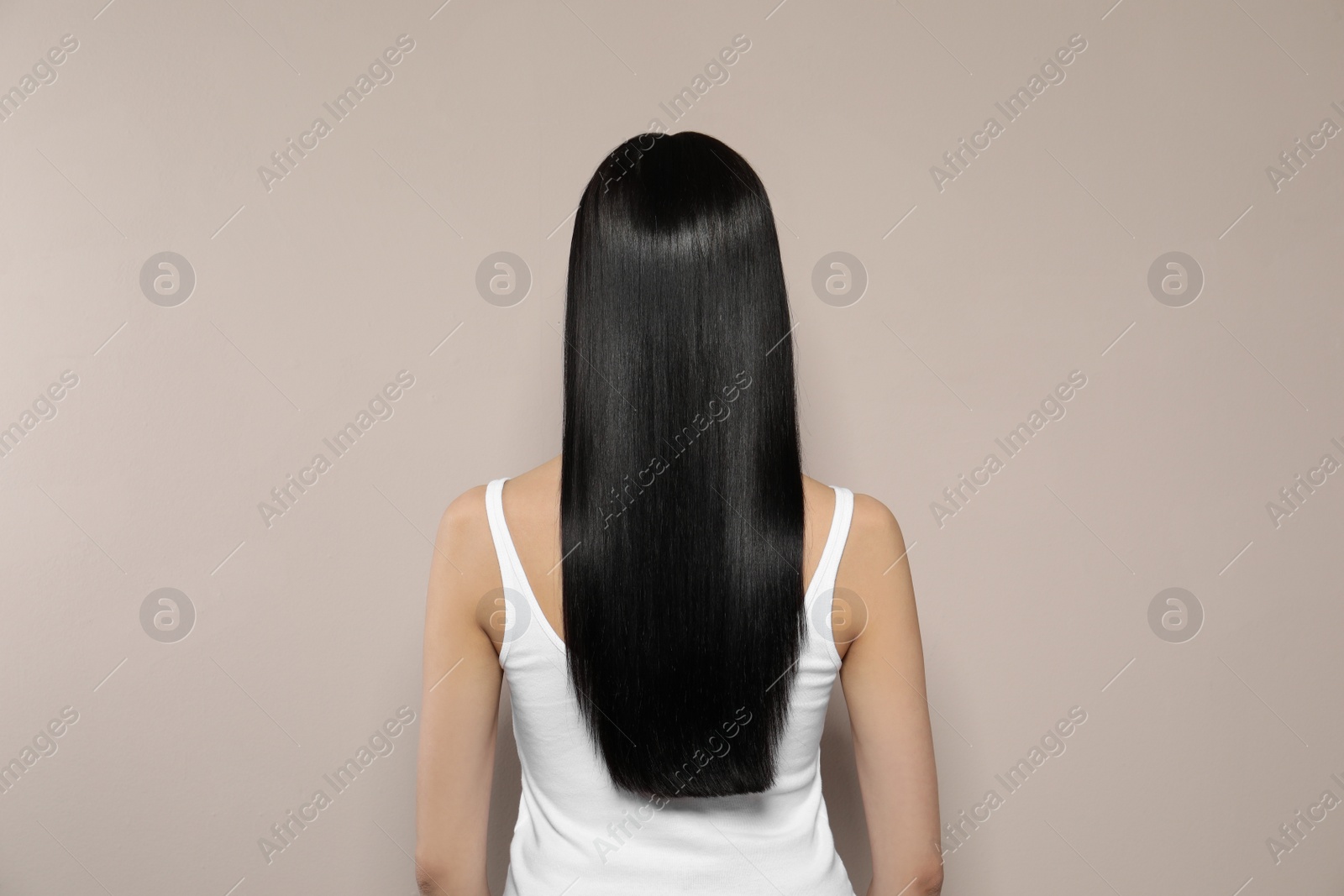 Photo of Young woman with long straight hair on beige background, back view