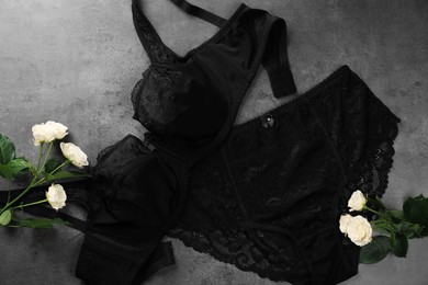 Photo of Elegant black plus size women's underwear and beautiful roses on grey background, flat lay