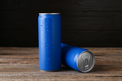 Energy drinks in wet cans on wooden table