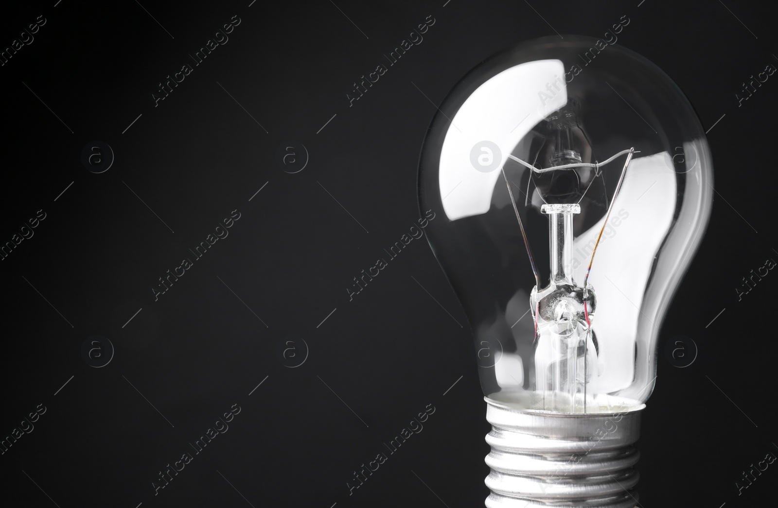 Photo of New modern lamp bulb on black background, space for text