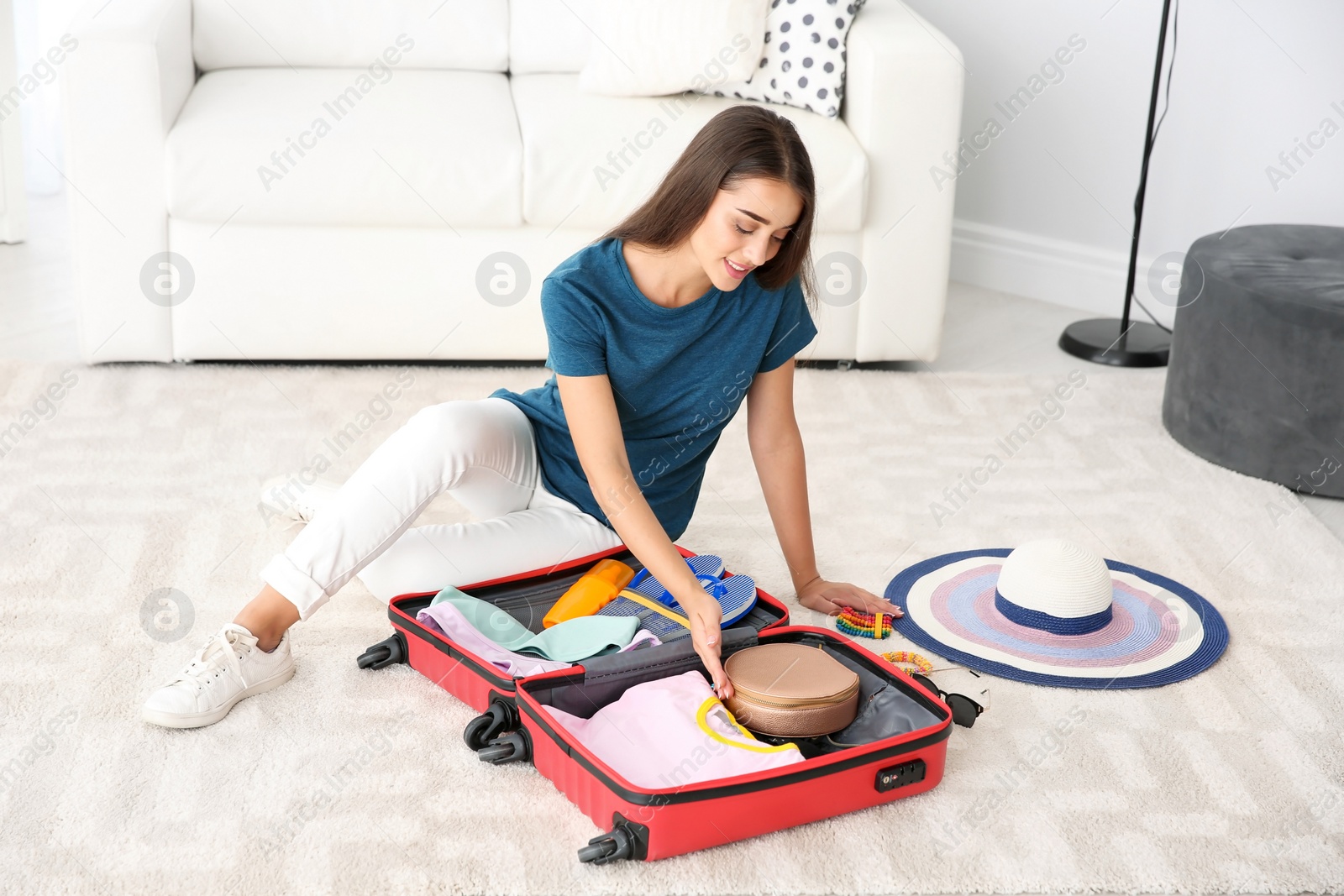 Photo of Young woman packing suitcase for summer journey at home