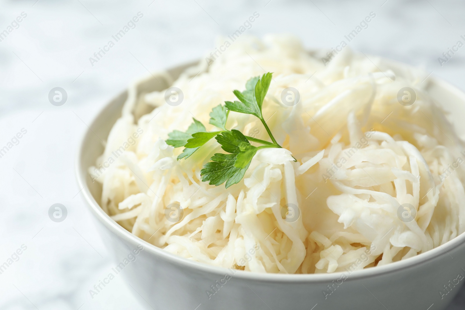 Photo of Tasty fermented cabbage with parsley on table, closeup